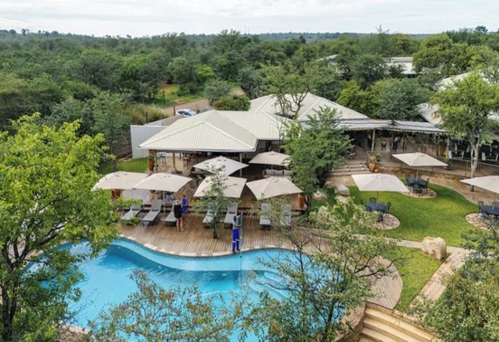 Aerial view of Insinka Lodge's curved pool, sun deck with umbrellas, and surrounding bush canopy, Victoria Falls, Zimbabwe