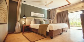 Stylish king bedroom with sage green feature wall, pendant lights, and garden views at Insinka Lodge, Victoria Falls, Zimbabwe