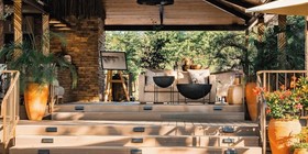 Raised outdoor lounge deck with terracotta pots and plush seating under a reed-and-timber pergola at Insinka Lodge, Victoria Falls, Zimbabwe