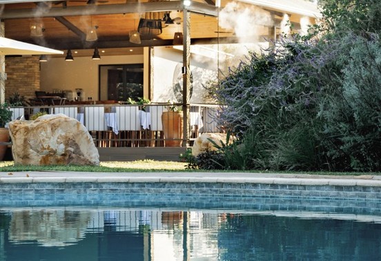 Insinka Lodge pool reflecting the open-air dining pavilion amid lush gardens, Victoria Falls, Zimbabwe