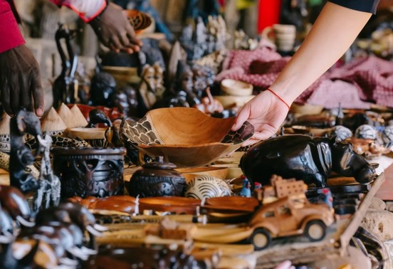 Guest browsing hand-carved wooden crafts at Maramba Market during a Mukuni Village tour, Livingstone, Zambia