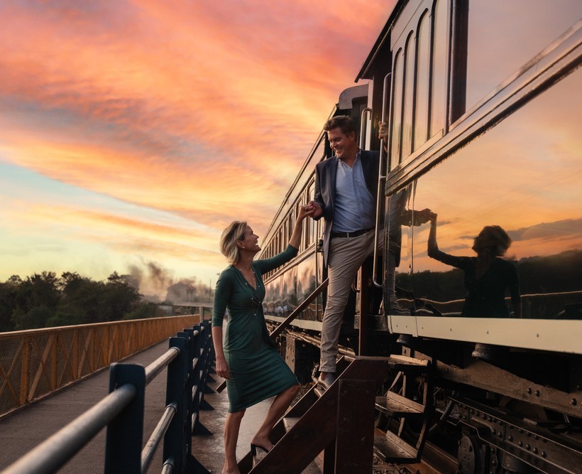 Couple boarding the Royal Livingstone Express heritage train at sunset on the Victoria Falls Bridge, Livingstone, Zambia