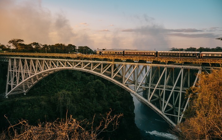 Royal Livingstone Express train crossing the historic Victoria Falls Bridge at sunset, Zambia