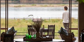 Guest gazing over the Zambezi River from Royal Zambezi Lodge's open-plan dining area, Lower Zambezi National Park, Zambia