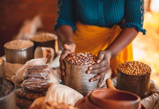Local woman displaying grains and produce at a Victoria Falls township market, Zimbabwe