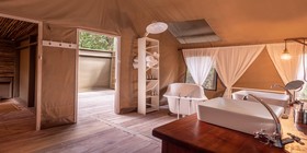 Freestanding clawfoot bathtub and vessel sink inside a luxury safari tent bathroom at Thamo Telele, Okavango Delta, Botswana