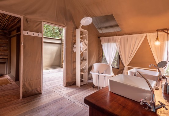 Freestanding clawfoot bathtub and vessel sink inside a luxury safari tent bathroom at Thamo Telele, Okavango Delta, Botswana