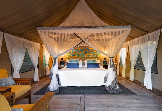 Luxurious king bed with mosquito net canopy inside a safari tent at Thamo Telele, Okavango Delta, Botswana